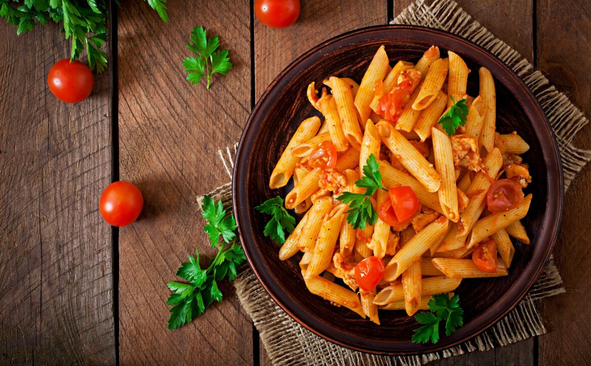 Penne pasta in tomato sauce with chicken and tomatoes  on a wooden table